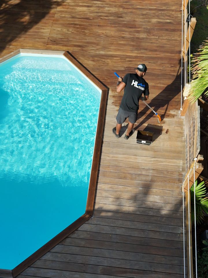 Harry, de HLMWASH, appliquant le saturateur sur une terrasse de piscine en bois